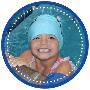 girl swimmer in swim cap smiling at edge of pool during swimming lessons